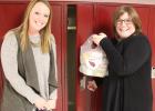Staples-Motley Elementary School Social Worker Hallie Bergeson (left) and Principal Kathy Johnson place a Cardinal Pax into a student’s backpack in their locker on Fridays which provides healthy food over the weekend. (Staples World photo by Mark Anderson)