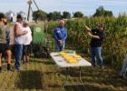 Amy Robak of Centra Sota, in black at right, shows Field Day attendees some of the cover crops planted amid the corn rows. Centra Sota is an agronomy cooperative working with CLC on the 60 inch corn rows and other creative planting experiments. The cover crops provide grazing for cattle once the corn is harvested, and remains as a fertilizer and protector of soil and water. (Staples World photo by Mark Anderson)
